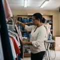 Dueña de una boutique revisando prendas colgadas en percheros metálicos.